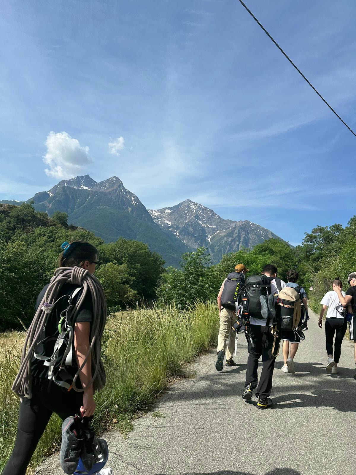 Friends walking toward the mountains with a rope and climbing shoes.